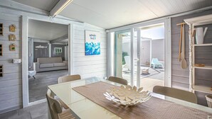 A modern interior with a dining area, a sofa, and a glass door leading to an outdoor patio. - Gorgeous home in Santa Croce Camerina (Santa Croce Camerina)