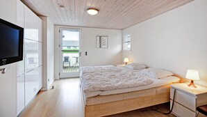 A bedroom with a bed, bedside lamps, a TV, and a door leading to a balcony. - Nice home in Sydals with sauna (Sydals)
