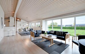 A spacious living area with a large window, a dining area, and a kitchen. - Nice home in Sydals with sauna (Sydals)