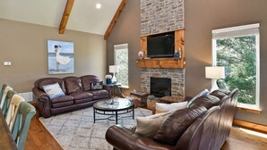 A cozy living room with a stone fireplace, leather sofas, and a television.