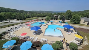 A swimming pool area with multiple lanes, sun loungers, and umbrellas.