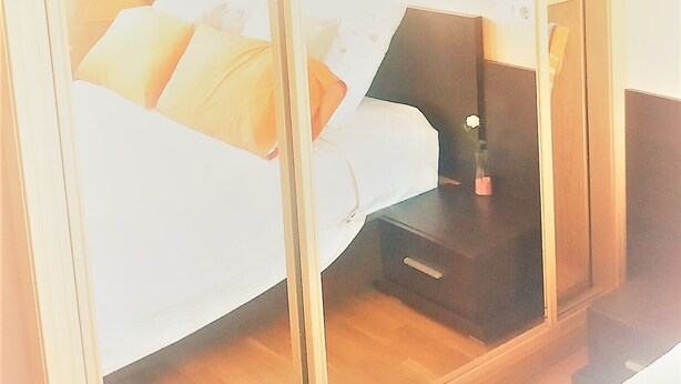 Une chambre à coucher comprenant un lit, une table de chevet, une commode et un miroir.