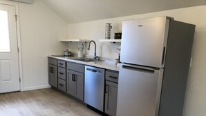 A modern kitchen with a stainless steel refrigerator, a dishwasher, and a sink. - Studio apartment on the banks of Yellowstone River (Gardiner)
