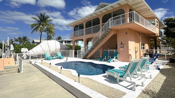 A two-story building with a swimming pool, outdoor seating, and a covered area. - Fish, Swim, Relax, Party - 4bd, 3ba - 75’ Dockage & Private POOL! (Marathon)
