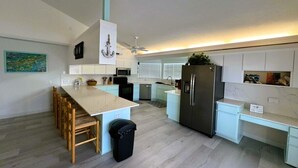 A modern kitchen with a central island, white cabinetry, and a stainless steel refrigerator. - Fish, Swim, Relax, Party - 4bd, 3ba - 75’ Dockage & Private POOL! (Marathon)