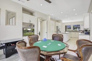 Uma sala de jantar com mesa verde, cadeiras e uma mesa de pôquer.
