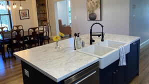 A kitchen with a marble countertop, black faucet, and pendant lights.