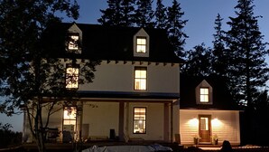 A two-story house with a porch, a front door, and a small garden area.
