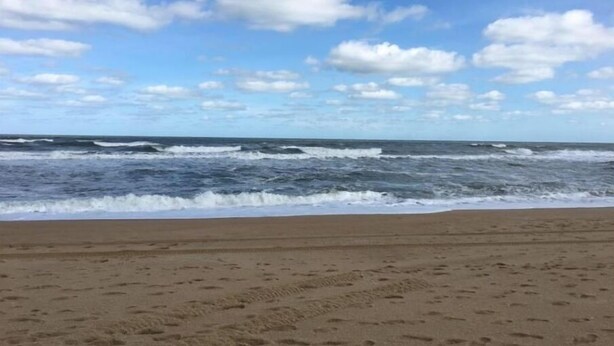 A beach with footprints in the sand and waves crashing onto the shore. - Oyster Pointe Flip Flop Stop Sound-side Condo (Kill Devil Hills)