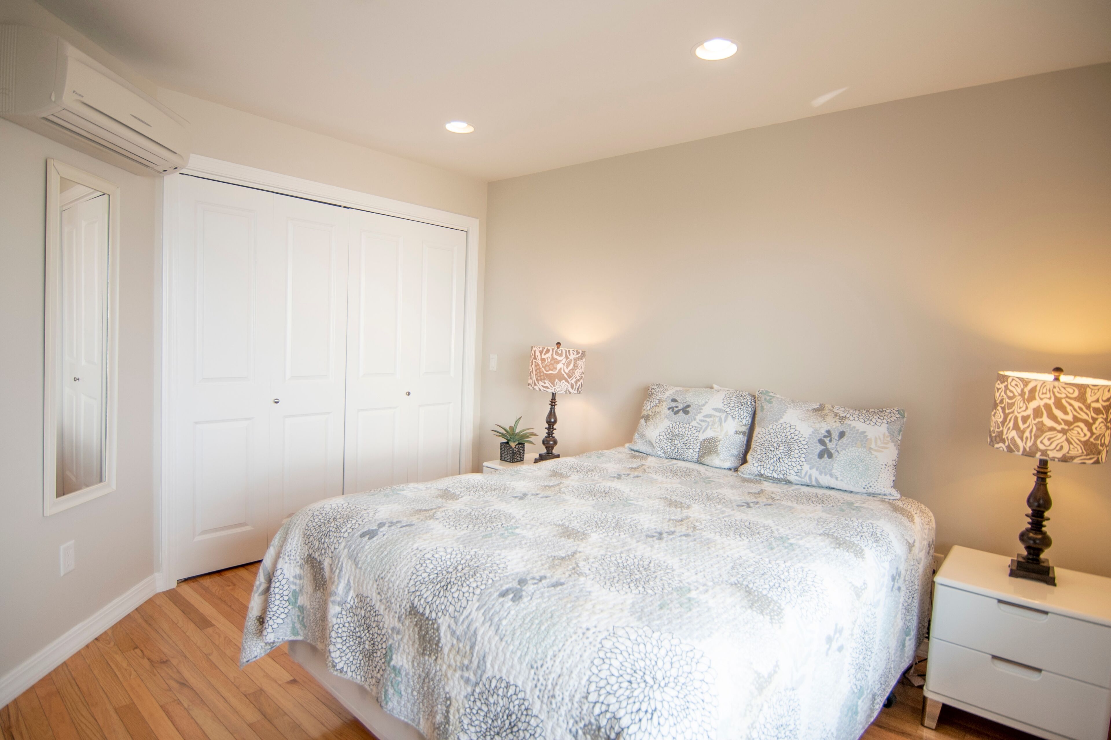 A bedroom with a bed, nightstands, a lamp, and a closet.