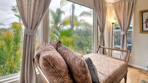 A room with a bed, a window with curtains, a lamp, and a framed picture on the wall.