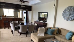 Un salon moderne avec un canapé beige, une table basse et un coin repas comprenant une grande table et des chaises.