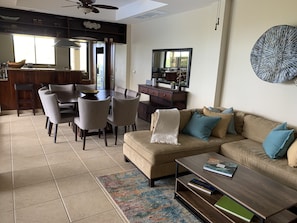 A modern living room with a beige sofa, a coffee table, and a dining area with a large table and chairs. - Standout Luxury Ocean View Villa (Playa Hermosa)