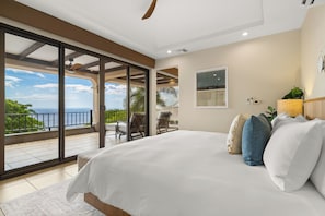 Un dormitorio con una cama grande, vistas al mar y un balcón con mobiliario exterior.