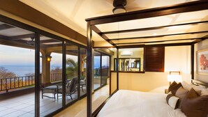 Une chambre avec un grand lit, un balcon donnant sur la mer et une porte-fenêtre coulissante.