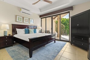 Un dormitorio con cama, mesitas de noche, cómoda y una puerta corrediza de vidrio que da a un balcón.