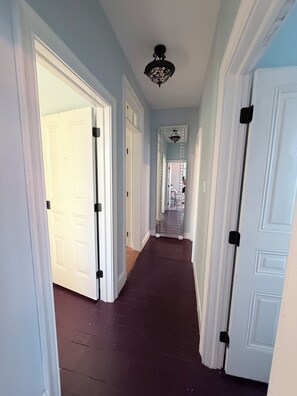 A hallway with white doors, a dark carpet, and a ceiling light fixture. - 1 Block from Cape May Beach & 10 min. walking distance to mall- 3rd Floor Unit (Cape May)