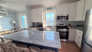 A kitchen with white cabinets, a large island with bar stools, a stove, microwave, and a refrigerator. - 1 Block from Cape May Beach & 10 min. walking distance to mall-3rd Floor Unit (Cape May)