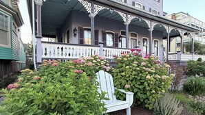 A two-story house with a porch, a white Adirondack chair, and a garden with various plants and flowers. - 1 Block from Cape May Beach & 10 min. walking distance to mall-3rd Floor Unit (Cape May)