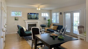 Una sala de estar con chimenea, una mesa de comedor con sillas, un sofá y un televisor montado en la pared.