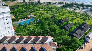 An aerial view of a resort with a swimming pool, palm trees, and a beach. - Celina Peninsula Resort (Dong Hoi)