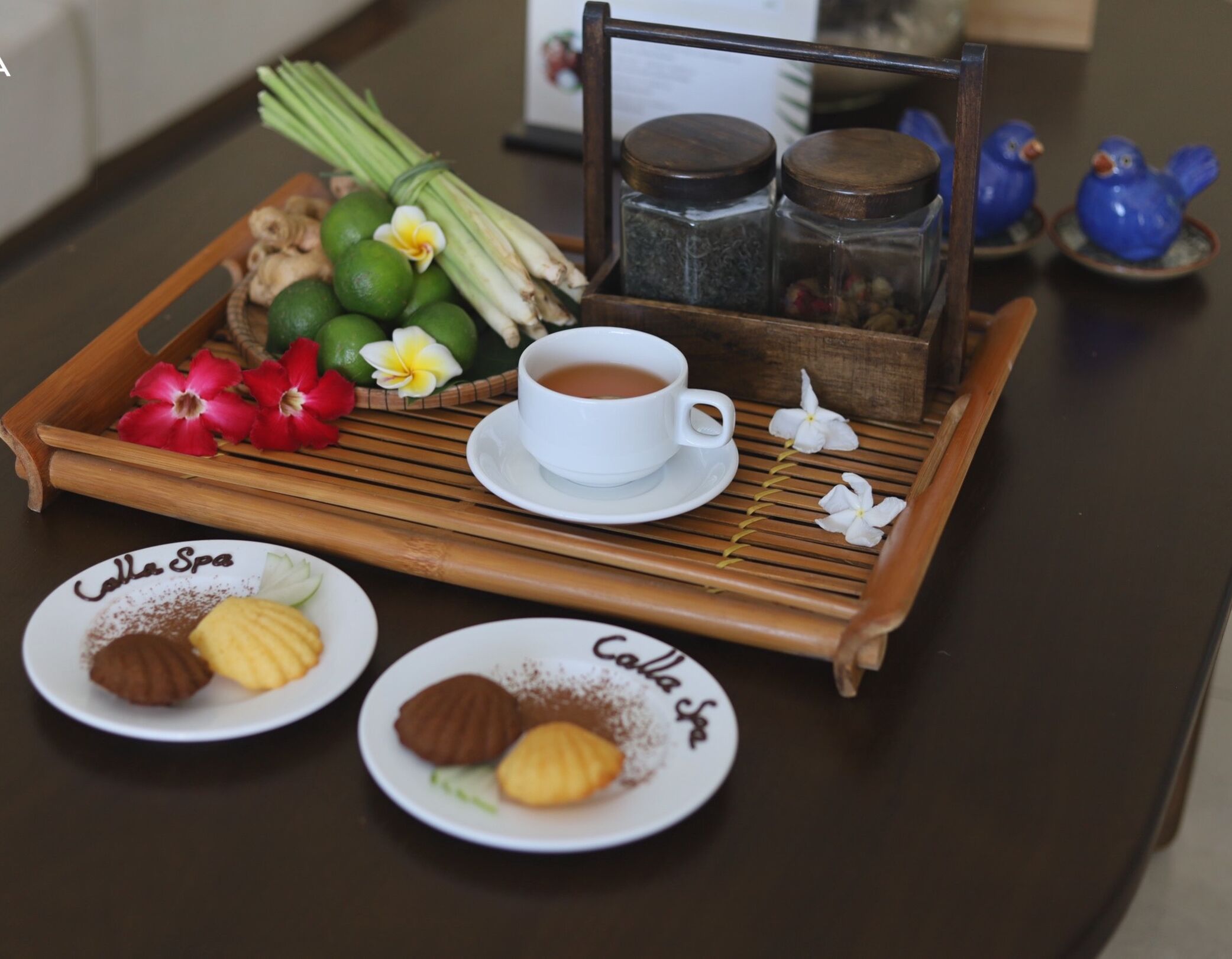 Un plateau avec une tasse de thé, deux assiettes de biscuits et un autre plateau en bois contenant des herbes fraîches et des fleurs.