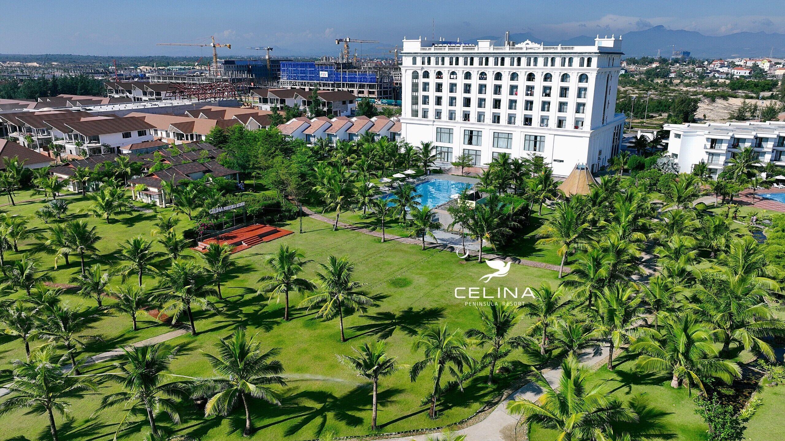 Un resort con un edificio grande, una piscina y palmeras.