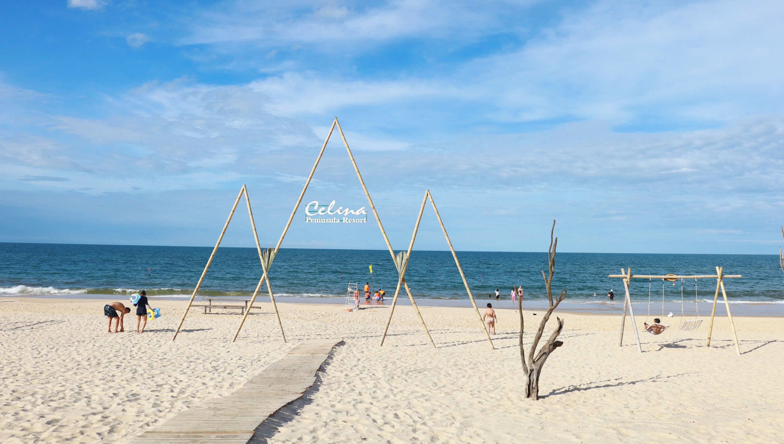 A beach with wooden swings and a clear sky.