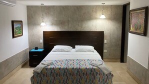 Ein Schlafzimmer mit einem großen Bett, zwei Nachttischen, einem Schreibtisch und einer Wand-Klimaanlage.