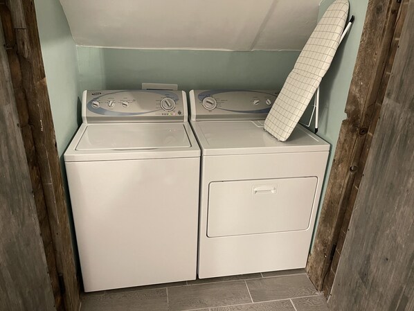 A laundry room with two stacked washers and dryers, a wooden door frame, and a tiled floor.