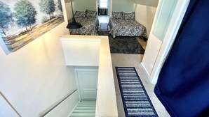 Eine schmale Treppe führt zu einem Schlafzimmer mit einem Bett und einem Schreibtisch.