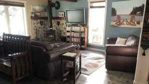 Un salon confortable avec une cheminée, un téléviseur et une bibliothèque.
