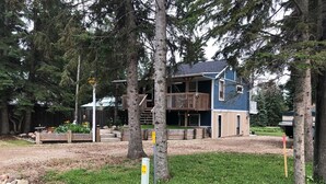 Un bâtiment à deux étages doté d’un balcon, entouré d’arbres et d’un jardin.