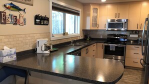 Une cuisine moderne dotée de plans de travail en granit, d’appareils électroménagers en acier inoxydable et d’armoires en bois.