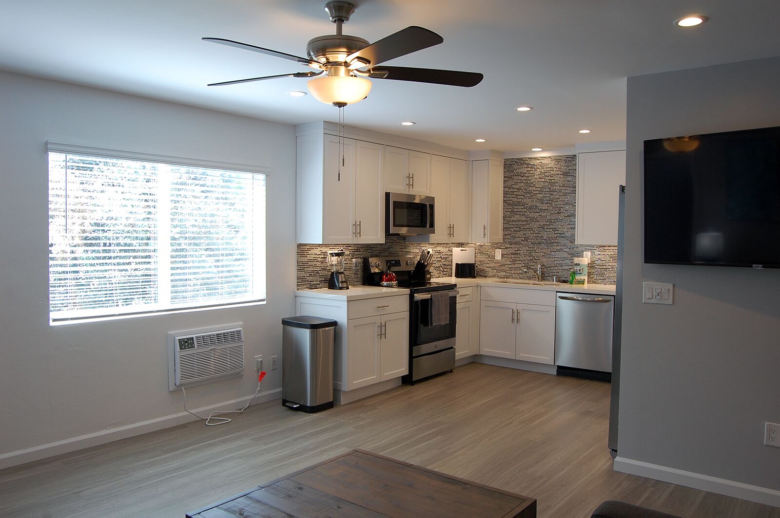 A modern kitchen with white cabinets, a black refrigerator, a microwave, and a brick-patterned backsplash.