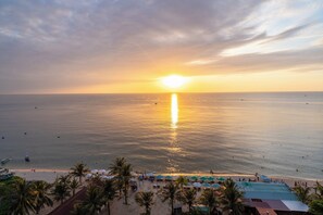 A beach view with a sunset, palm trees, and beach umbrellas. - Maris Beach Hotel Phu Quoc (Phu Quoc)