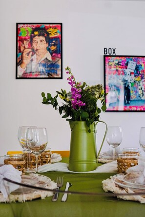 A dining table with a green tablecloth, a green pitcher with flowers, and two framed artworks on the wall. - Billard, Déco Tendance & Détente Entre Terre et mer (La Landec)