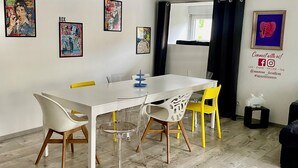 A modern dining area with a white table, clear chairs, and a wooden floor.