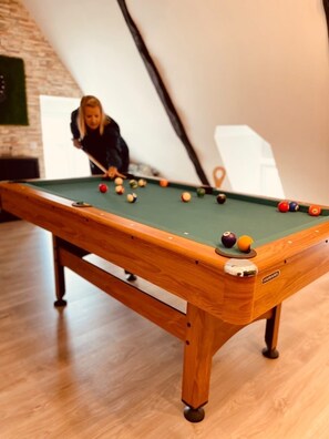 A pool table with balls, a person playing, and a brick wall in the background. - Billard, Déco Tendance & Détente Entre Terre et mer (La Landec)