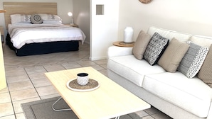 Ein modernes Schlafzimmer mit Bett, Nachttisch und einer Couch.