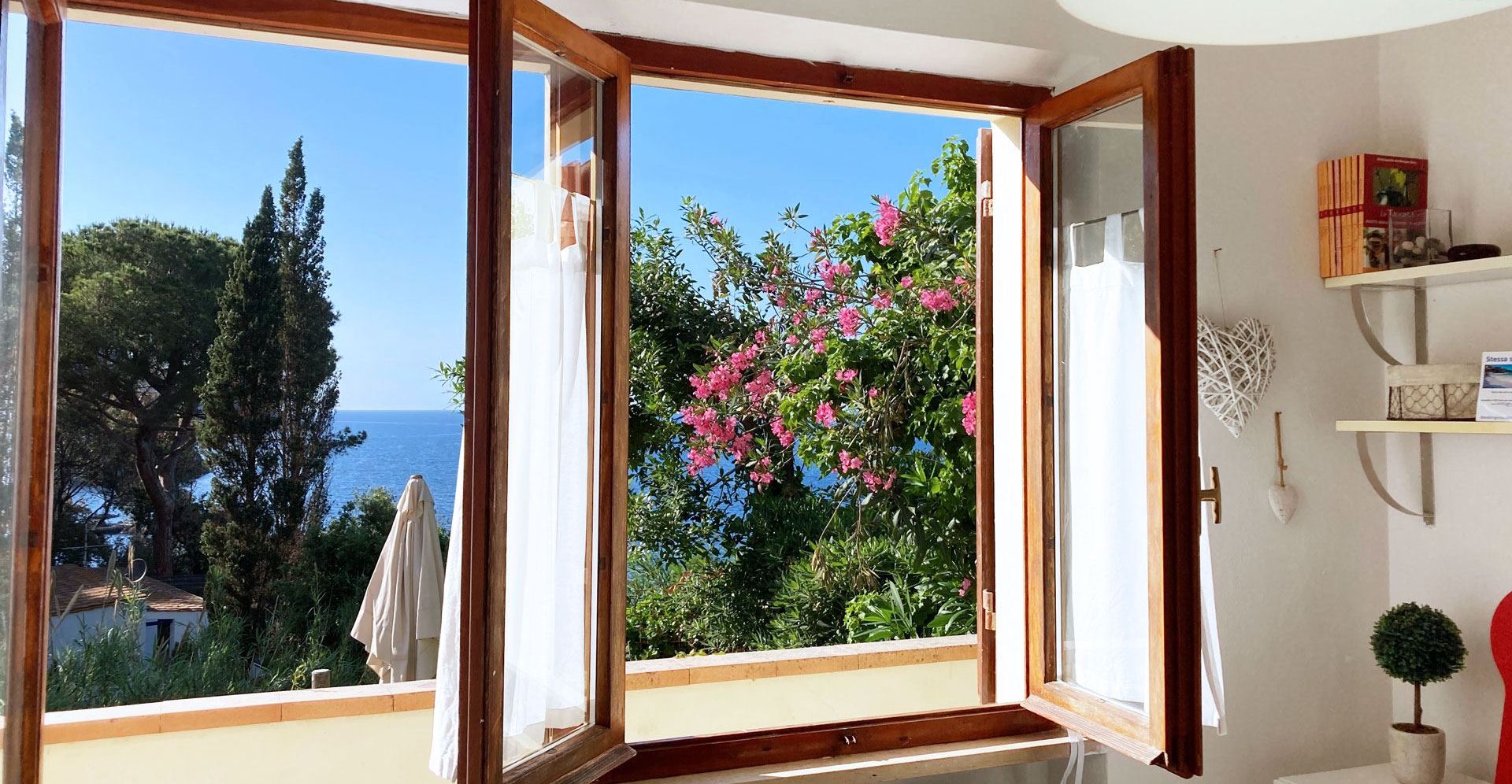 Una habitación con un amplio ventanal que ofrece vistas al mar y a los árboles.
