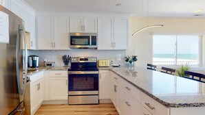 Una cocina moderna con armarios blancos, electrodomésticos de acero inoxidable y encimera de granito.