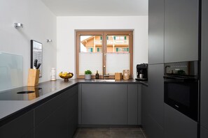 A modern kitchen with a built-in oven, a sink, and a window with a view of a building.