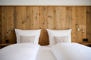 A double bed with white bedding, wooden headboard, bedside tables with lamps, and a small nightstand.