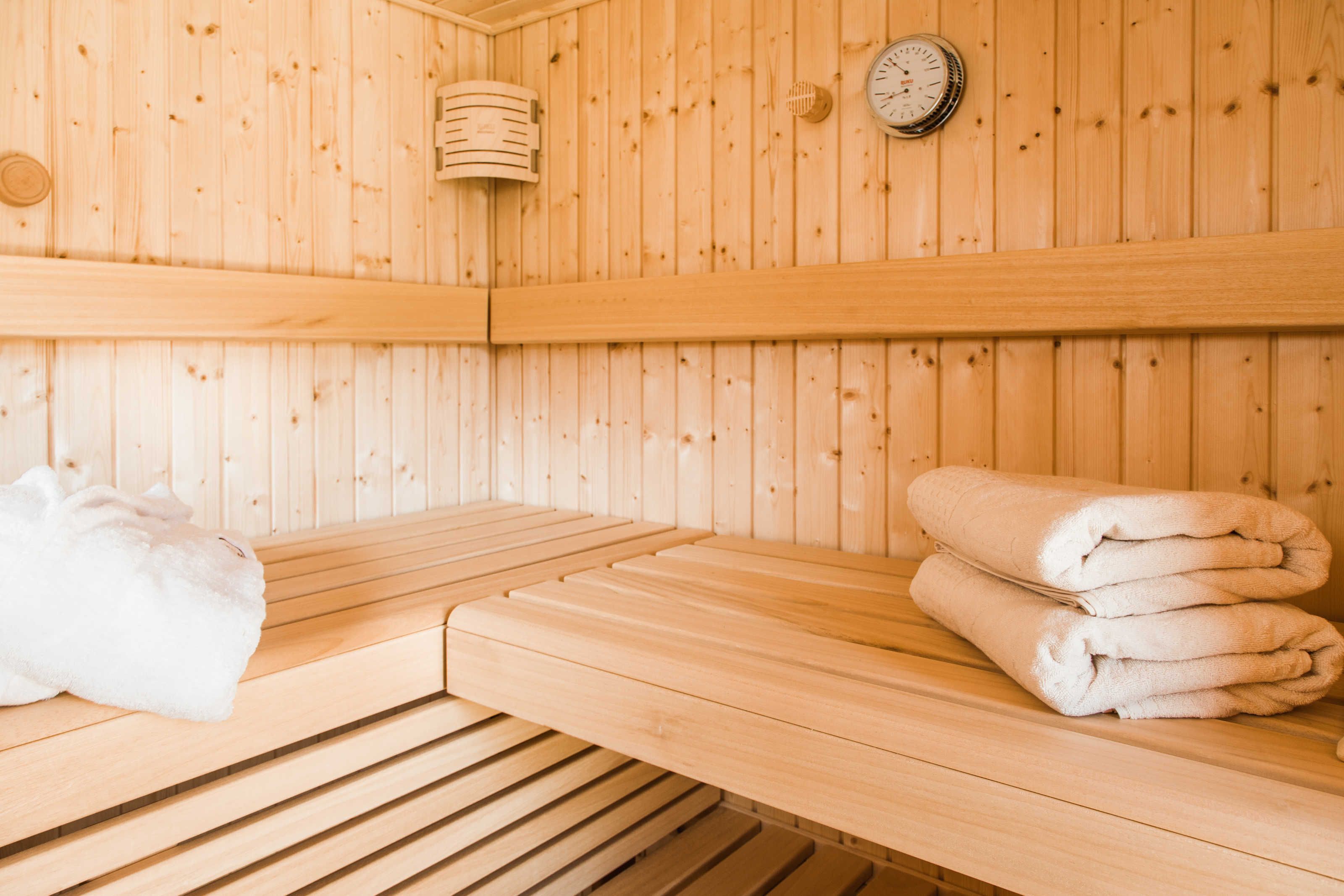 A wooden sauna room with benches and towels.
