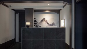 A reception desk with a dark marble top, a wall-mounted lamp, and a framed artwork depicting a mountain landscape. - Anook Hotel and Spa Daejeon Yuseong (Daejeon)