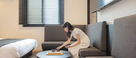 A modern room with a bed, a sofa, and a small round table with a tray.