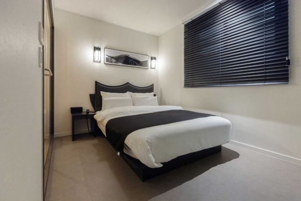 Une chambre moderne avec un lit, une table de chevet et un luminaire fixé au mur.