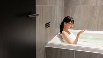 A person in a bathtub with a caution sign on the wall.