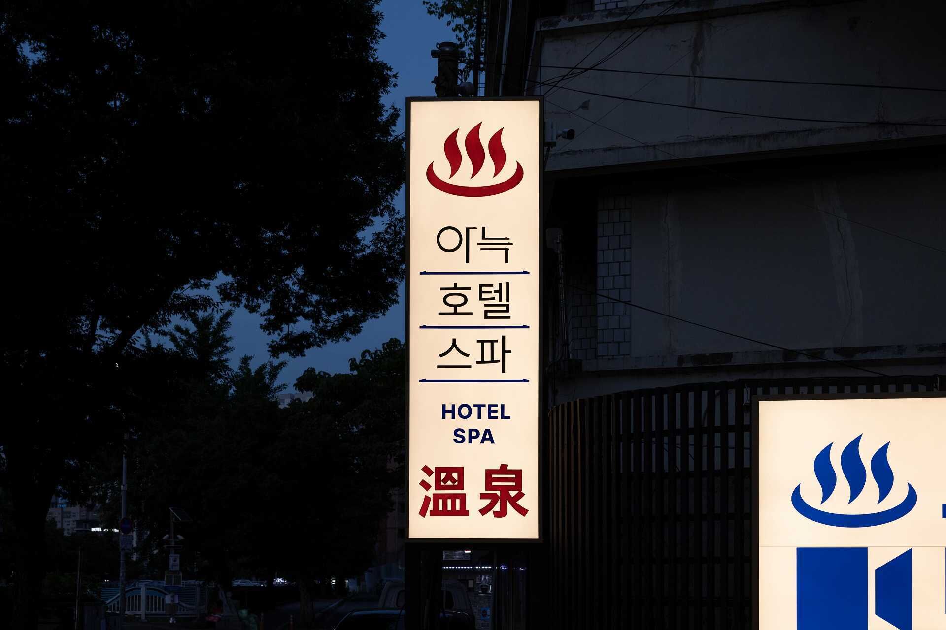 A sign for a hotel and spa with Korean text and a flame symbol.
